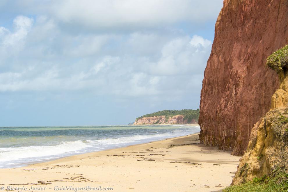 Imagem das falesias e do mar calmo da Praia Japara Mirim.